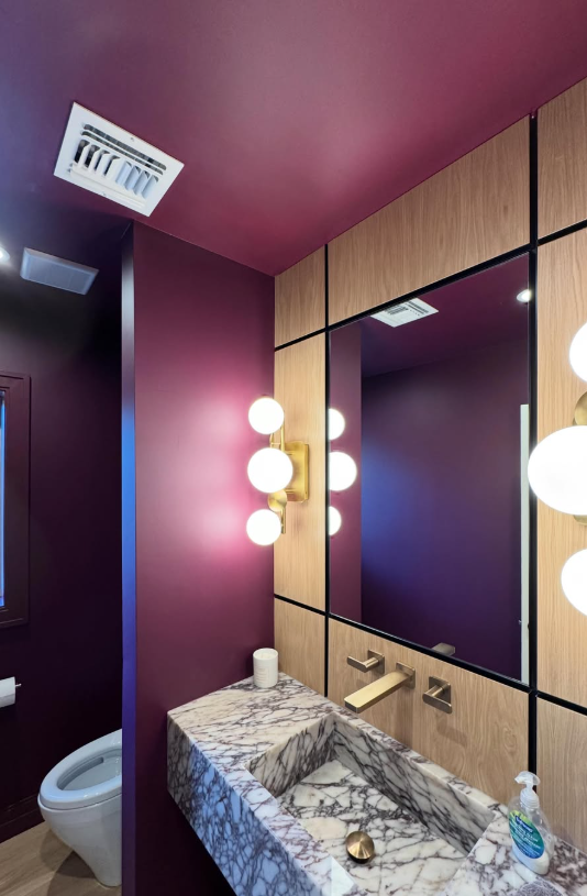 Powder room with brass sconces and marble vanity