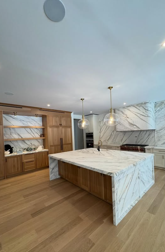 Marble waterfall island kitchen with brass pendant lighting